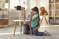 Happy mother and smiling daughter sitting on floor and looking at wooden pyramid at home