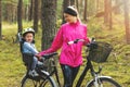 Happy mother with son in bike child seat cycling on forest trail