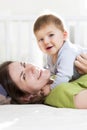 Happy mother and son playing and having fun in bed. Royalty Free Stock Photo