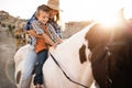 Happy mother and son riding a horse at sunset - Main focus on kid hands