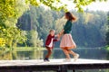 Happy mother and son on a wooden pier on the lake in autumn. A woman and a child are dancing, spinning, holding hands Royalty Free Stock Photo