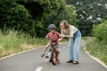 Happy Mother teaches child son to ride a bike on the bike path Royalty Free Stock Photo