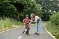 Happy Mother teaches child son to ride a bike on the bike path Royalty Free Stock Photo