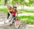 Happy mother teaches his daughter to ride a bike