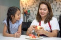 happy Mother teaching daughter peeling red apples together on table in kitchen at home . loving family.  child girl excited Royalty Free Stock Photo