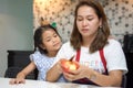 happy Mother teaching daughter peeling red apples together on table in kitchen at home . loving family.  child girl excited Royalty Free Stock Photo