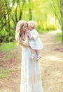 Happy mother tenderly kissing her baby holding on hands in spring