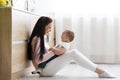 Happy mother tickling her cute baby son on kitchen floor Royalty Free Stock Photo