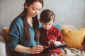 Happy mother and toddler son using tablet at home. Family playing computer or searching internet Royalty Free Stock Photo