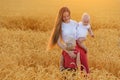 Happy mother with two children walking through wheat field at sunset Royalty Free Stock Photo