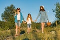 Happy mother and two daughters holding hands walking along rural country road with wildflowers, basket of berries. Sunny summer Royalty Free Stock Photo