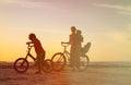 Happy mother with two kids biking at sunset