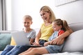 Happy mother using laptop with her children on sofa at home Royalty Free Stock Photo