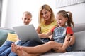 Happy mother using laptop with her children on sofa at home Royalty Free Stock Photo