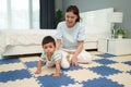 happy mother watching her infant baby crawlinf on play mat or jigsa floor in bedroom Royalty Free Stock Photo