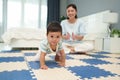 happy mother watching her infant baby crawlinf on play mat or jigsa floor in bedroom Royalty Free Stock Photo