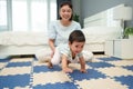 happy mother watching her infant baby crawlinf on play mat or jigsa floor in bedroom Royalty Free Stock Photo