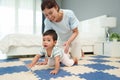 happy mother watching her infant baby crawlinf on play mat or jigsa floor in bedroom Royalty Free Stock Photo