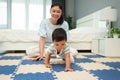 happy mother watching her infant baby crawlinf on play mat or jigsa floor in bedroom Royalty Free Stock Photo