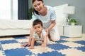 happy mother watching her infant baby crawlinf on play mat or jigsa floor in bedroom Royalty Free Stock Photo