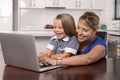 Blond mother woman together with her young beautiful and sweet little girl 6 to 8 years old sitting at home kitchen enjoying with Royalty Free Stock Photo