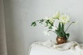 Happy Mothers day. Beautiful white tulips and daffodils in vintage vase on wooden table against rustic wall. Stylish simple spring Royalty Free Stock Photo