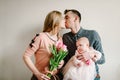 Happy mothers day! Daughter with dad congratulate mom and give her bouquet of flowers tulips. Happy family kissing. Royalty Free Stock Photo