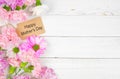 Happy Mothers Day gift tag with side border of flowers on a white wood background Royalty Free Stock Photo