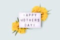 Happy Mothers Day. Lightbox with quote and frame made of yellow narcissus.