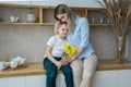 Happy mothers day! little son gives flowers to mom, boy congratulates mom, flowers in the hands of a boy, yellow daffodils, happy
