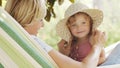 Happy mothers day, smiling mom playing with her blue eyed little girl daughter child, plays with her by putting on a big straw hat Royalty Free Stock Photo