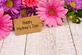 Happy Mothers Day tag close up with flowers over white wood Royalty Free Stock Photo