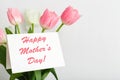 Happy Mothers Day text on gift card in flower bouquet on white background. Greeting card for Mom. Flower delivery, Congratulations Royalty Free Stock Photo