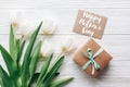 happy mothers day text sign on stylish craft present box and greeting card and tulips on white wooden rustic background. flat lay Royalty Free Stock Photo