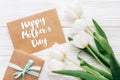 happy mothers day text sign on stylish craft present with greeting card and tulips on white wooden rustic background. flat lay wi Royalty Free Stock Photo