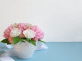 Bouquet of flowers on blue surface in front of white wall.