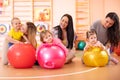 Happy mothers and their babies on fitness ball in nursery. Gimnastics for kids on fitball. Royalty Free Stock Photo