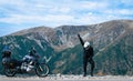Happy motorcyclist man is dancing and Adventure Motorbike on the top of the mountain. Motorcycle trip. World Traveling, Lifestyle