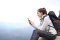 Happy mountaineer checking phone in the mountain