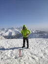 Happy mountaineer reaches the top of a snowy mountain in a sunny winter.