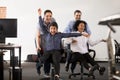 Happy multi-ethnic office people having fun riding on chairs Royalty Free Stock Photo