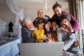 Happy multi-generation diverse family gathering around notebook and having fun during a video call Royalty Free Stock Photo