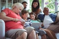 Happy multi-generation family using laptop, mobile phone and digital tablet Royalty Free Stock Photo