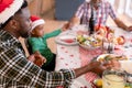 Happy multi generation family wearing santa hats, praying together, having christmas meal Royalty Free Stock Photo