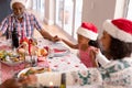 Happy multi generation family wearing santa hats, praying together, having christmas meal Royalty Free Stock Photo