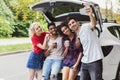 Happy travelers sitting near car