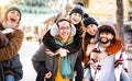 Happy multicultural friends walking at winter travel location on piggyback move - Everyday life style concept