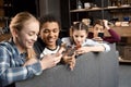 Happy multicultural teenagers group using smartphones and sitting on sofa at home