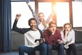 Happy multicultural teenagers playing video games with joysticks at home Royalty Free Stock Photo