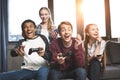 Happy multicultural teenagers playing video games with joysticks at home